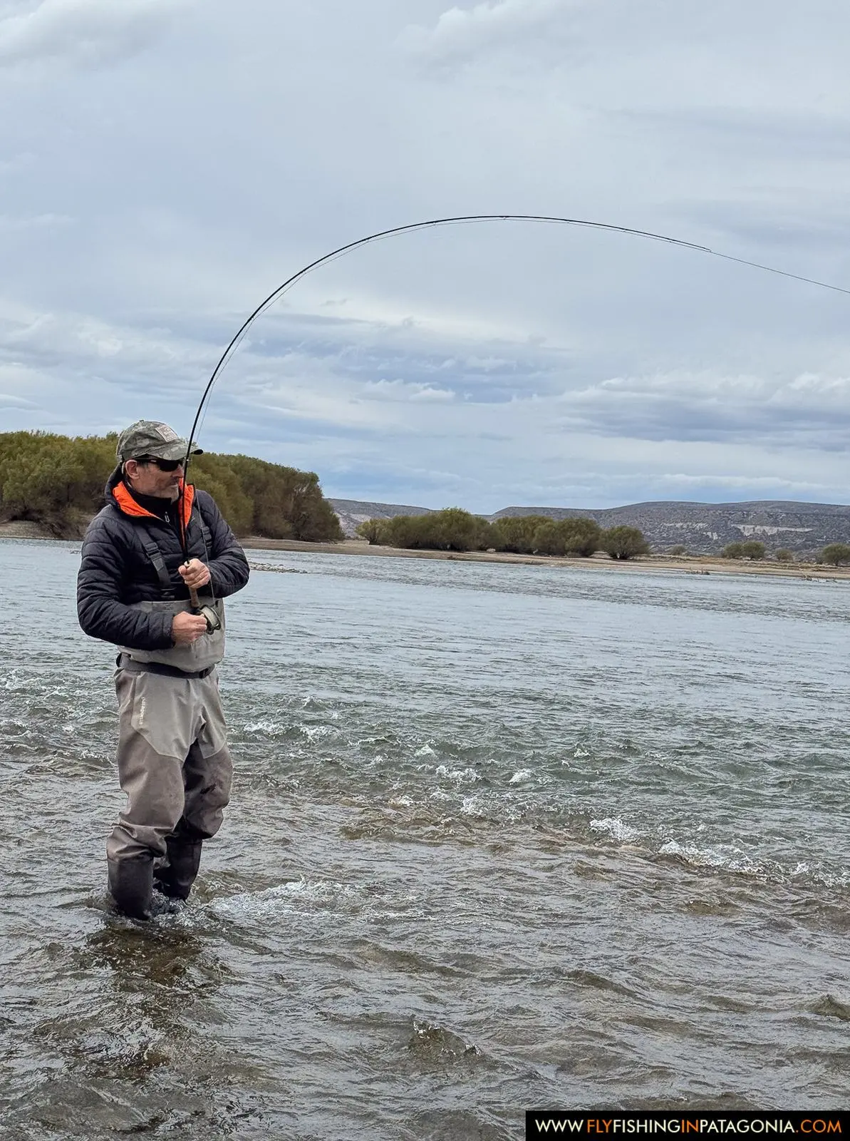 Fly angler fighting a trout while wading the Collon Cura River