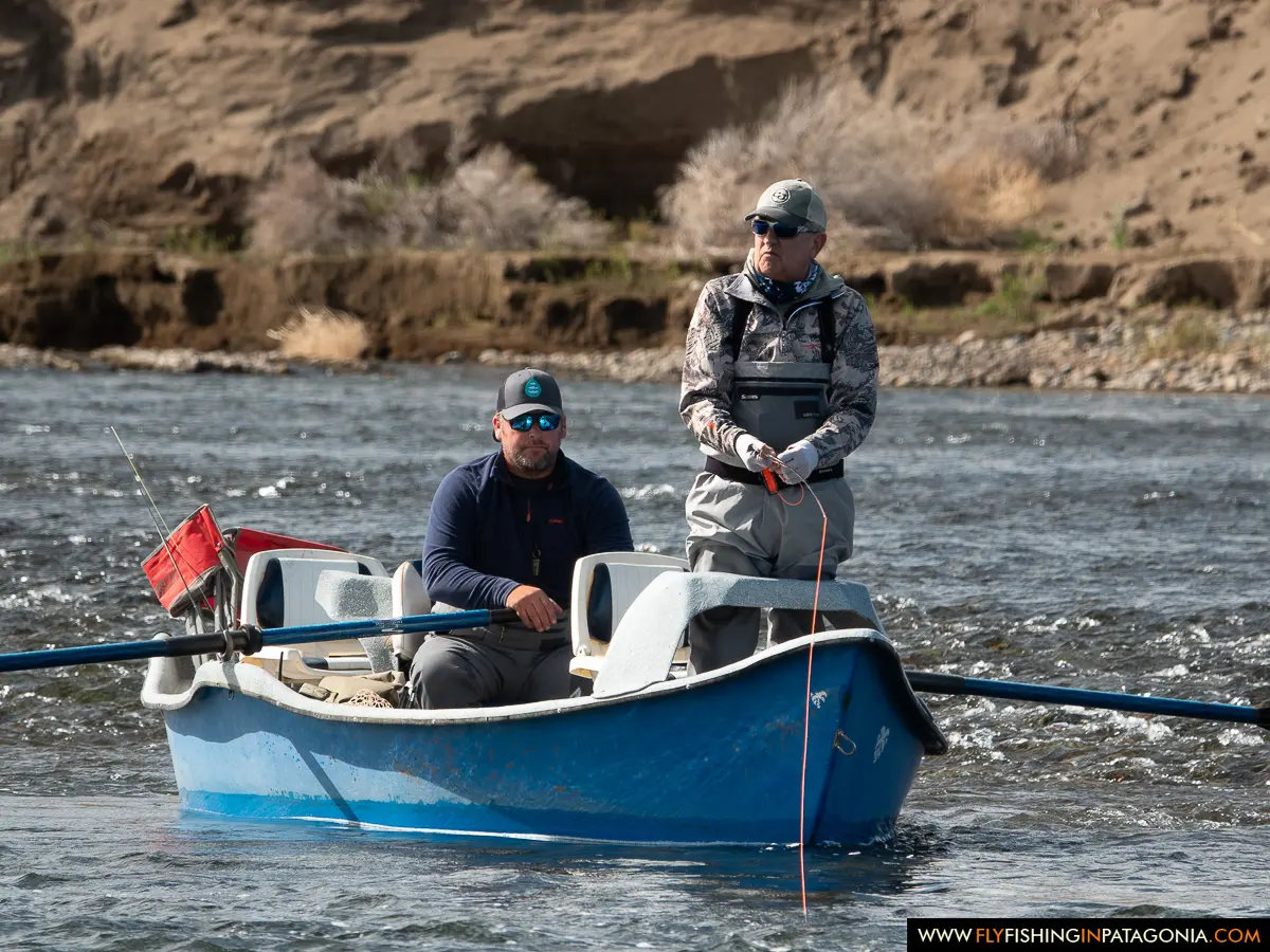 Two anglers fishing from a blue drift boat on the Collon Cura River
