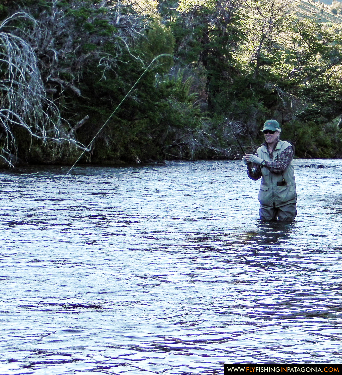 Fly angler fighting a trout in a shaded Huaca Mamuil run