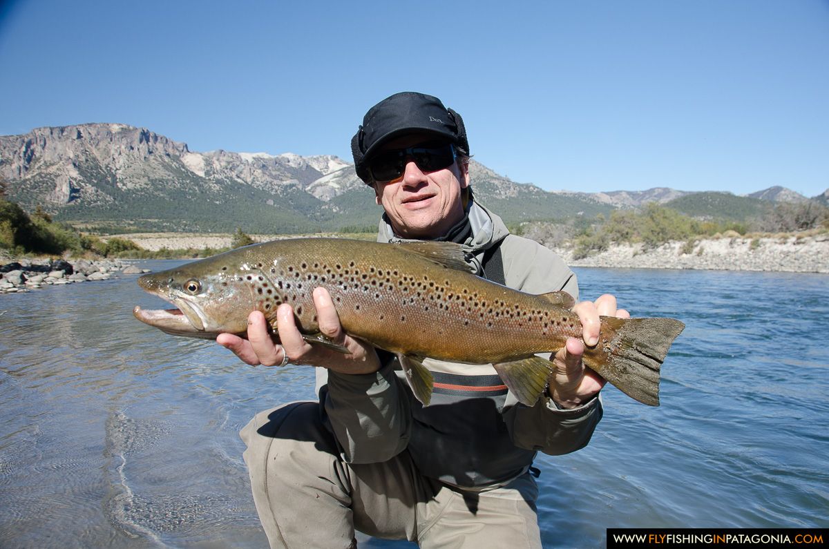 Angler holding a brown trout with the Traful mountains behind