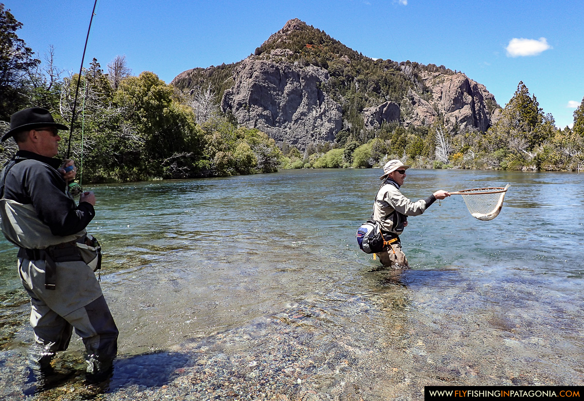 Anglers landing a trout in a mountain run on the Traful